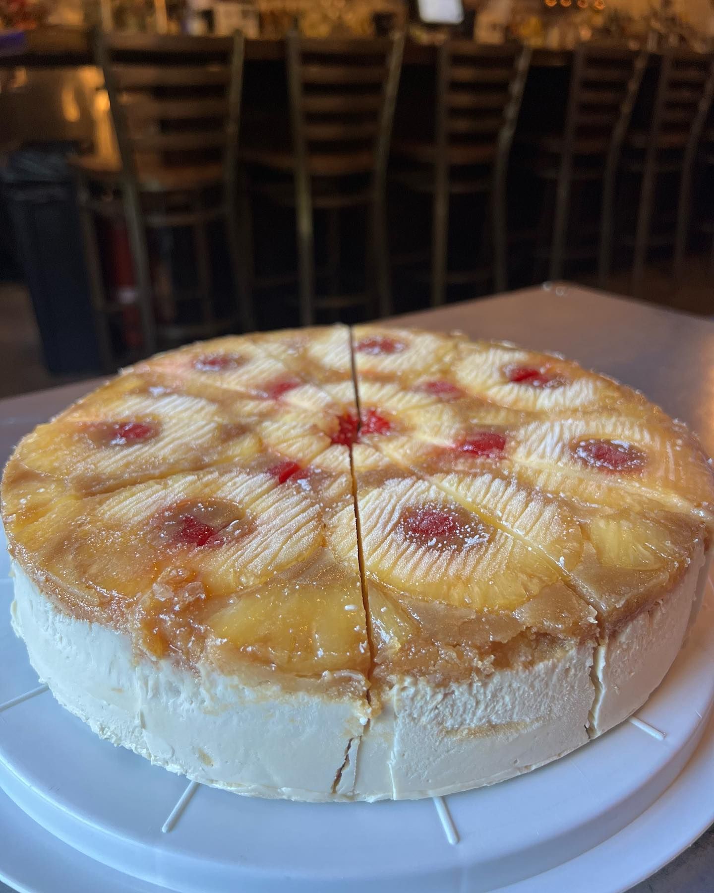 A pineapple upside down cheesecake is sitting on a white plate on a table.