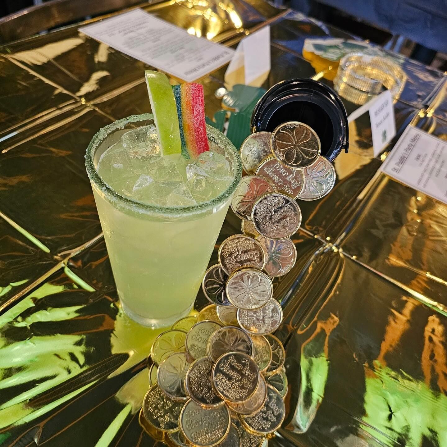 A drink in a glass next to a pile of coins