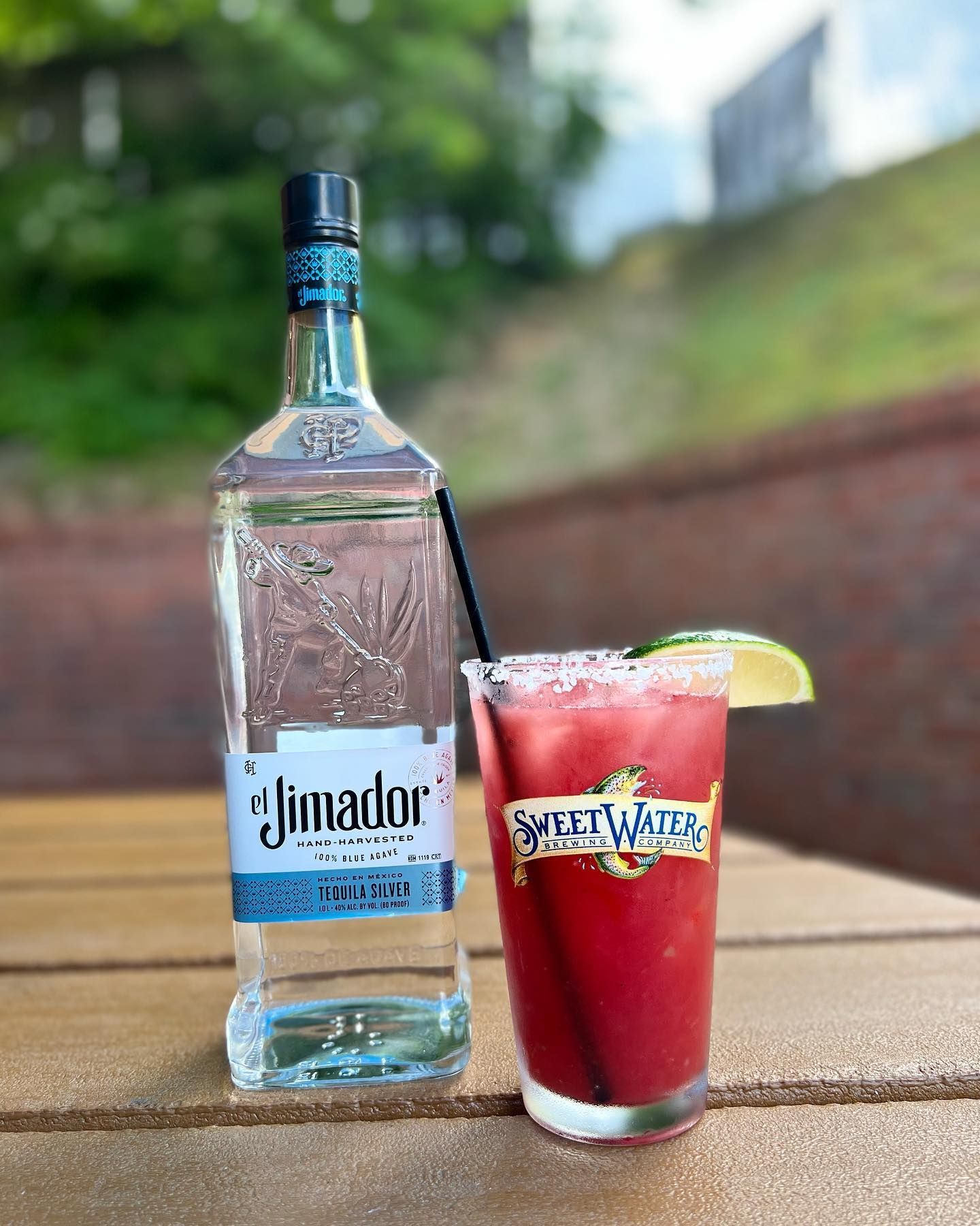 A bottle of jimador tequila and a glass of sweet water on a table.