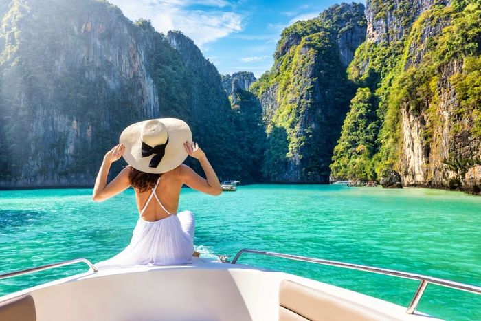 A woman is sitting on the back of a boat in the ocean.