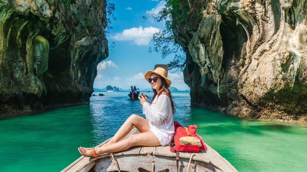 A woman is sitting in a boat in the ocean taking a picture.