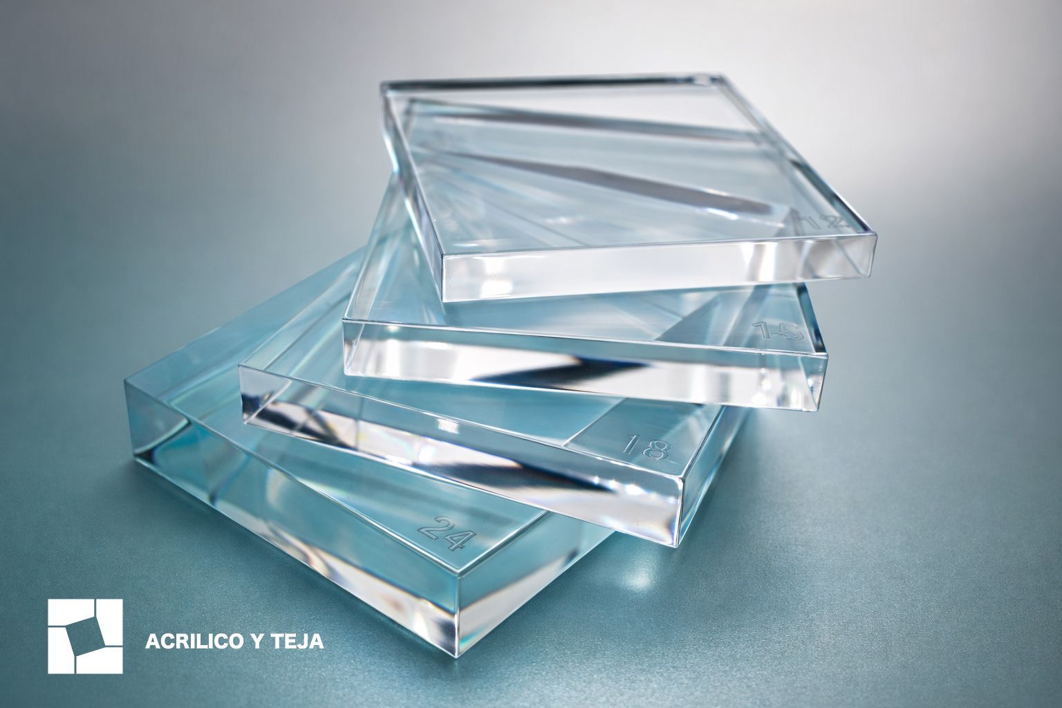 Una pila de láminas cuadradas, gruesas y transparentes de acrílico o vidrio, que descansan sobre una superficie azul claro, con el logotipo de una marca en una esquina.
