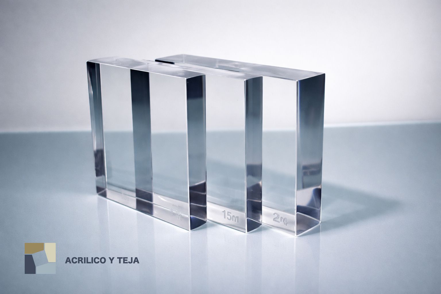 Dos bloques rectangulares de acrílico transparente colocados sobre una superficie blanca lisa y reflectante.