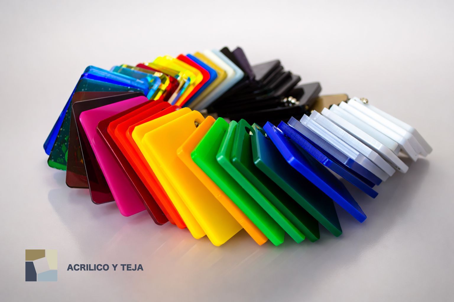 Un conjunto de muestras en forma de abanico, compuestas por láminas acrílicas translúcidas de colores, dispuestas en un espectro sobre un fondo blanco.
