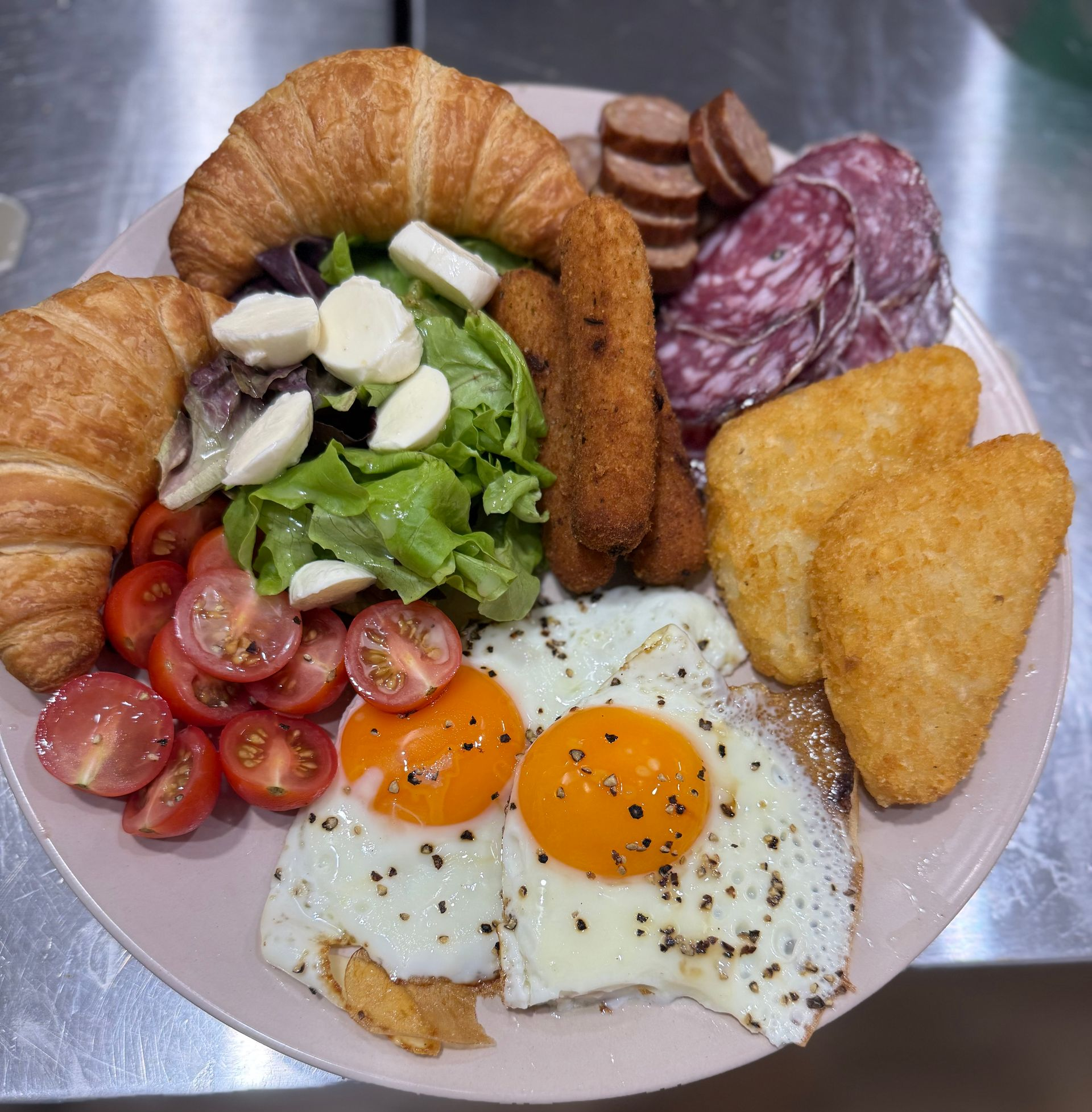 Plate with croissants, salad, tomatoes, eggs, hash browns, salami, and sausages — Relax in Paradise in Yeppoon, QLD