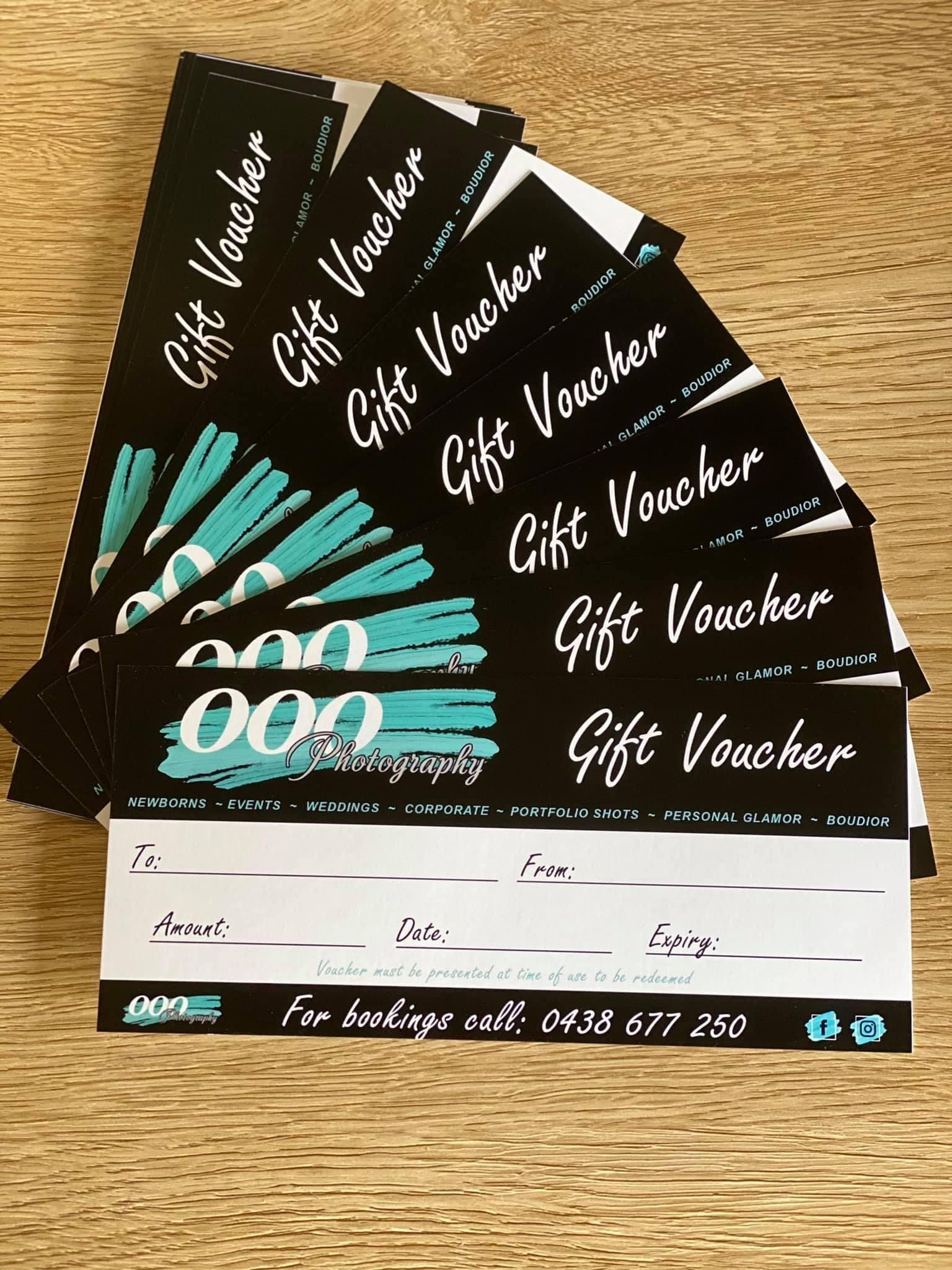 Fan of black gift vouchers with teal accents on a wooden surface.