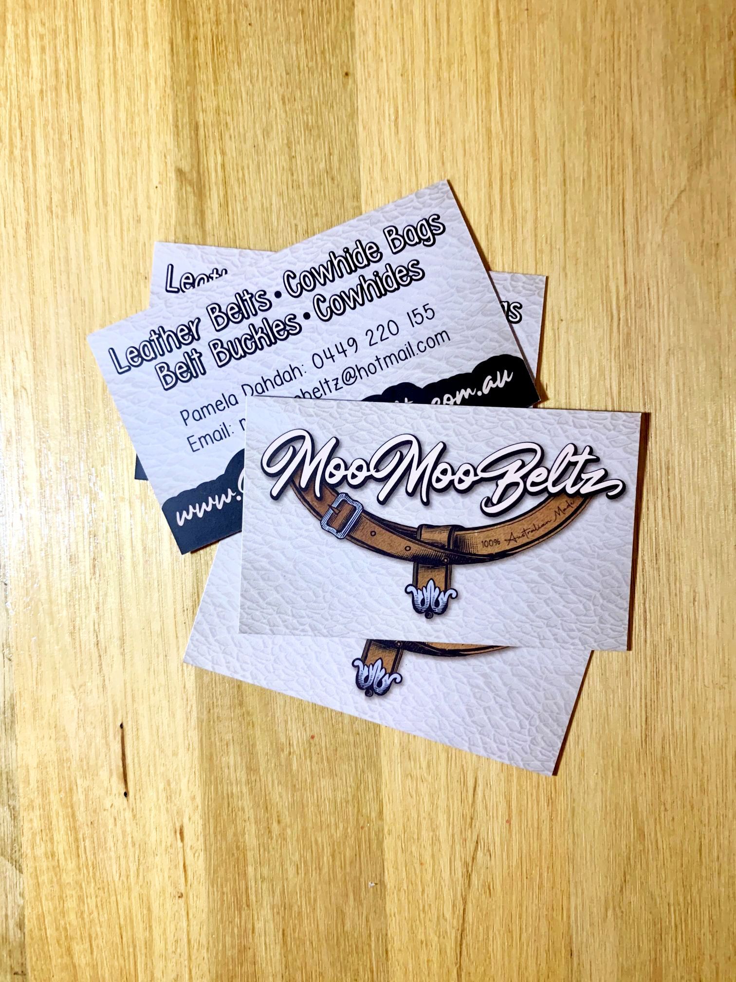 Business cards for Mos Mos Belts on a wooden surface.
