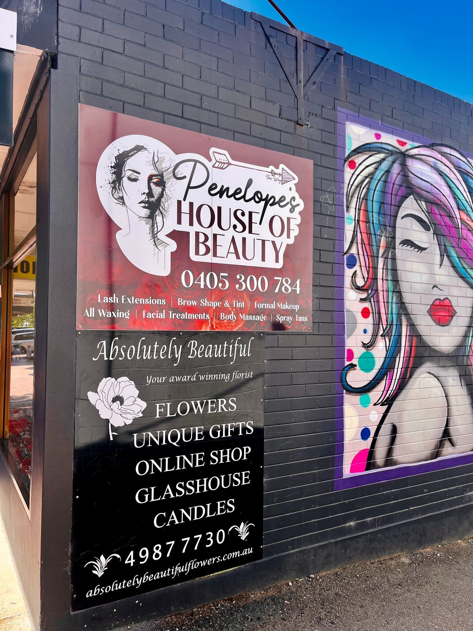 Sign for Penelopes House of Beauty and A Flowers and Gifts Shop on A Black Brick Wall — Stuckup Industries in Morisset, NSW