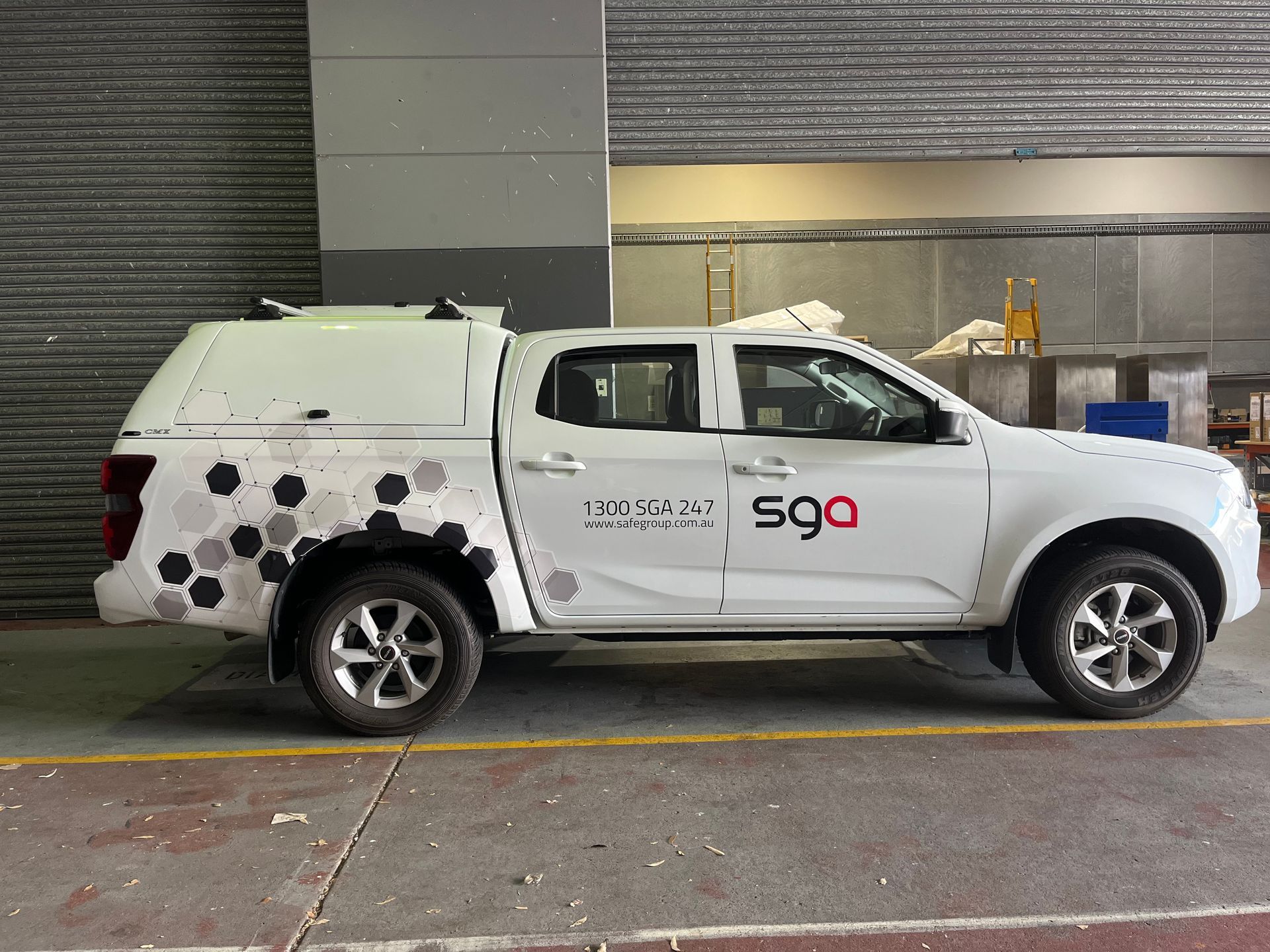 White pickup truck with a canopy and company logo parked indoors.