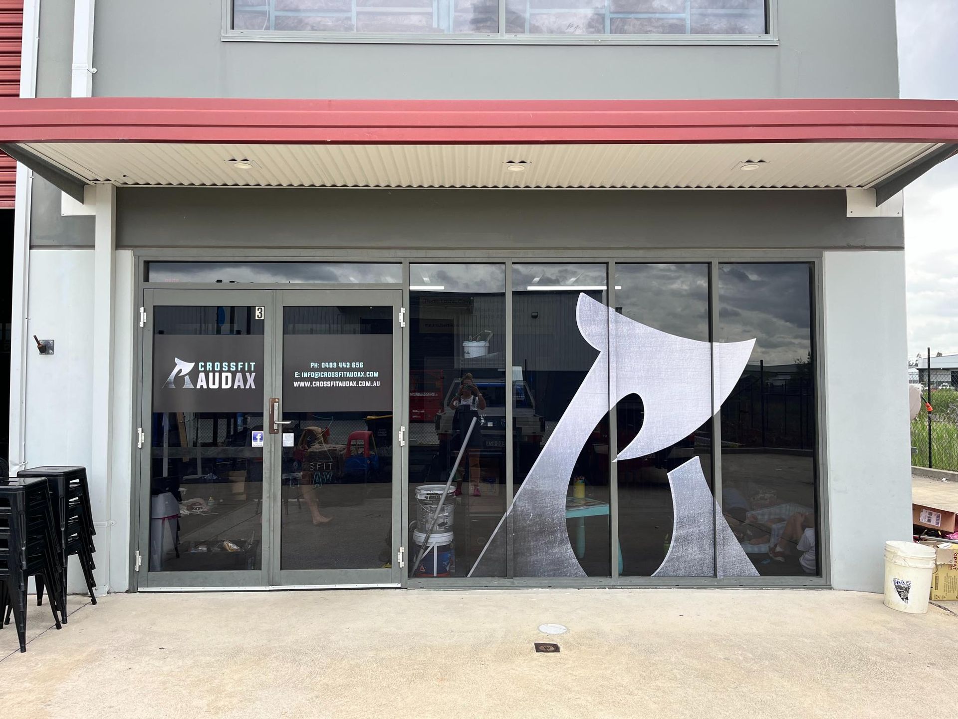 Exterior of a building with glass doors and a large stylized 