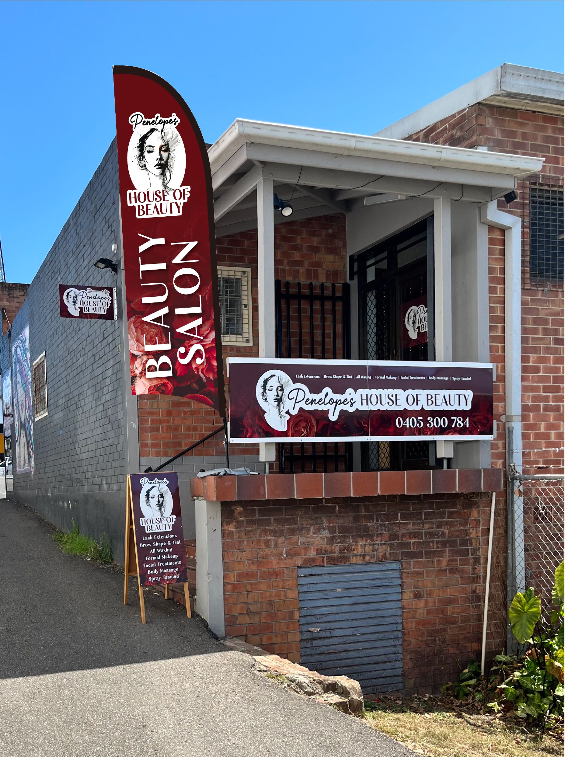 Beauty Salon Exterior with Red and White Sign, Flag, and Sandwich Board — Stuckup Industries in Morisset, NSW