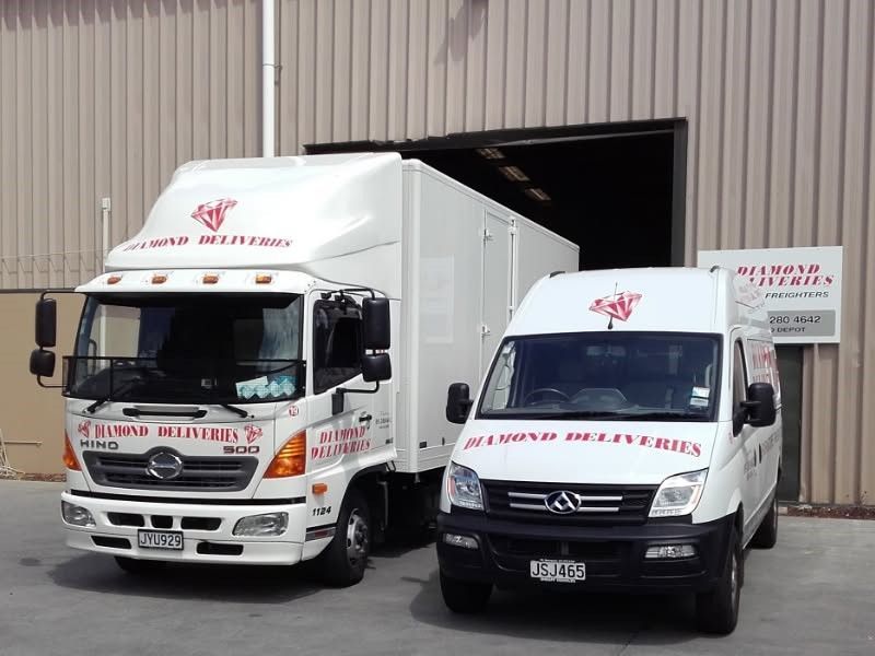 Two white trucks are parked in front of a building that says services