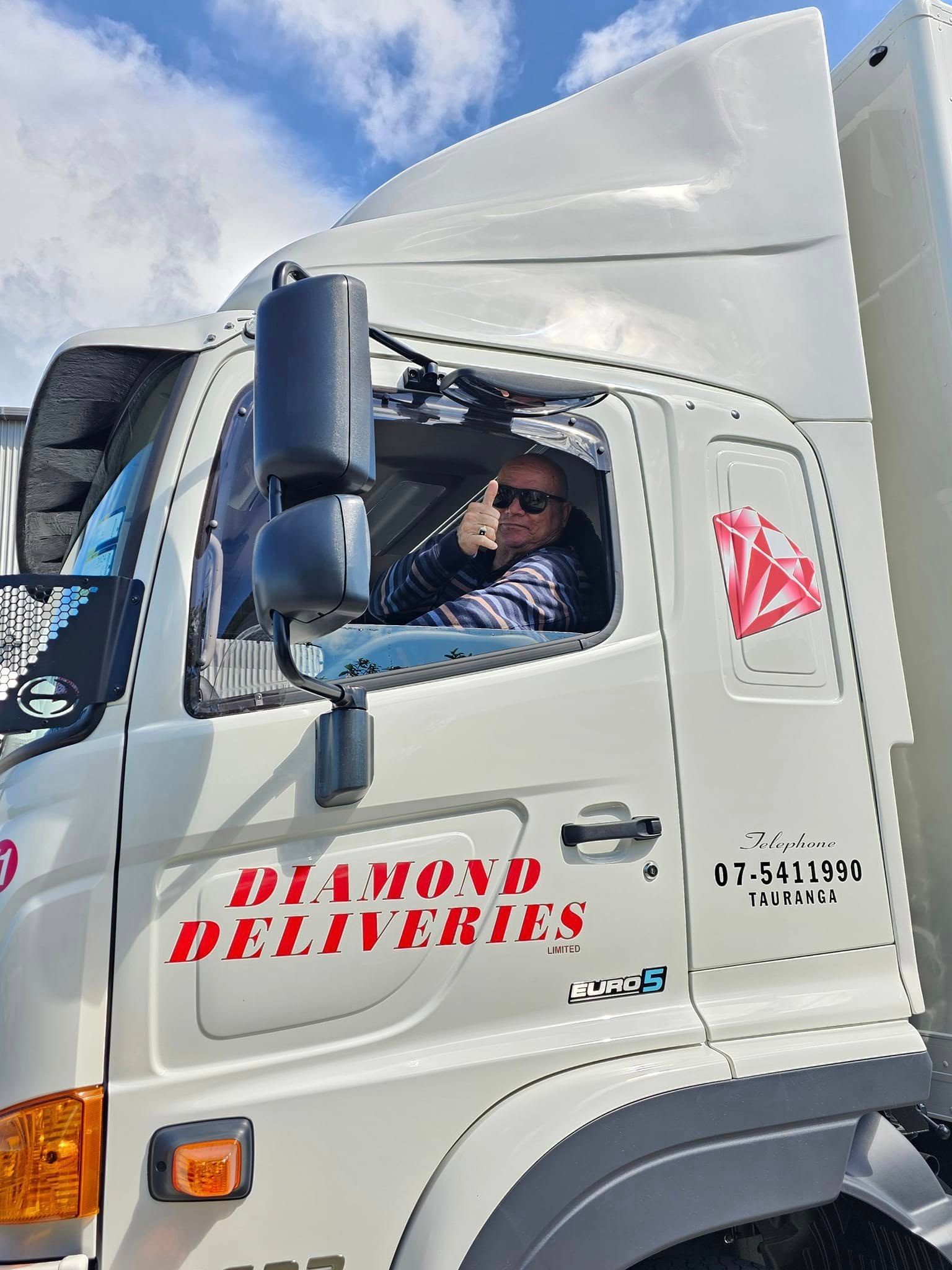 A man is sitting in the driver 's seat of a diamond deliveries truck.