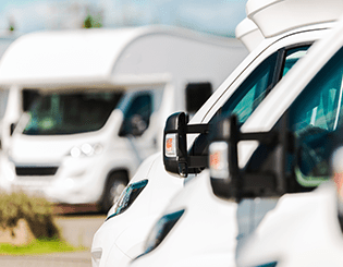 White RVs parked in a row, with side mirrors and windshields visible.