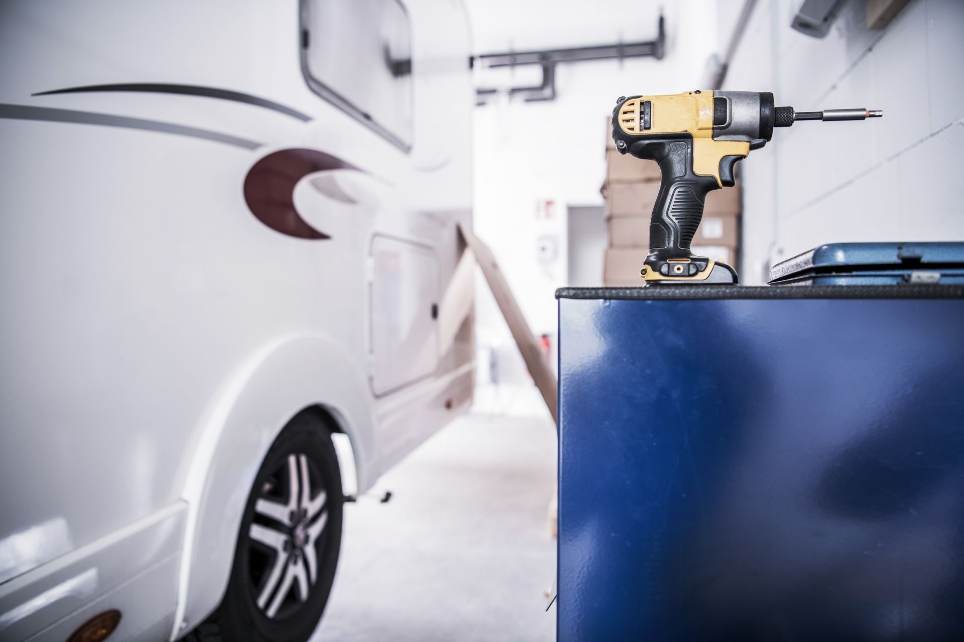 Camper van in a repair shop next to a yellow drill. Camper van in a repair shop next to a yellow drill.