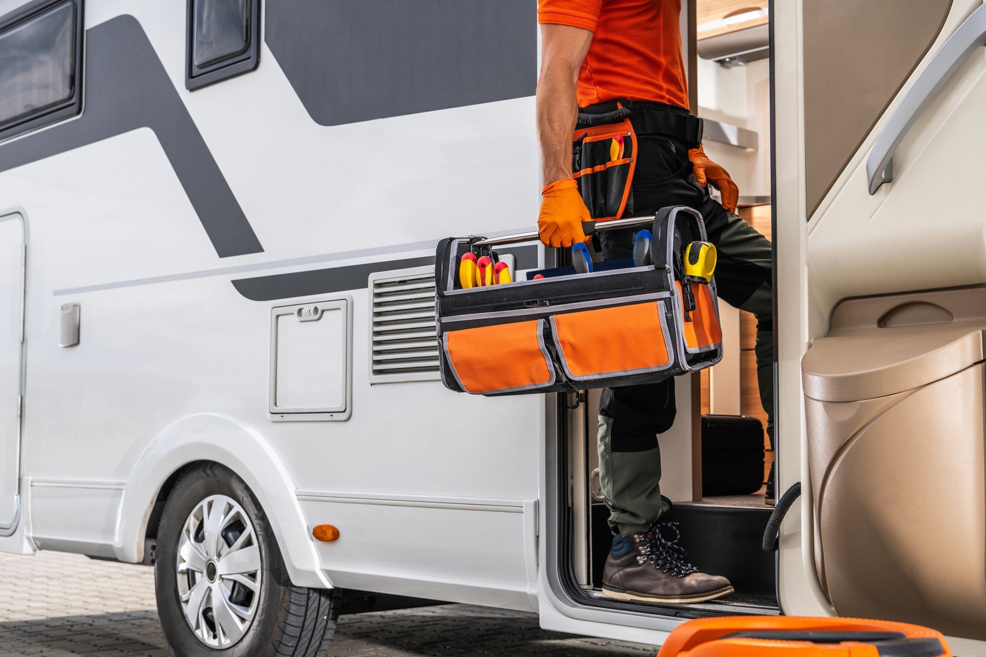 RV technician entering a motorhome with toolbox.