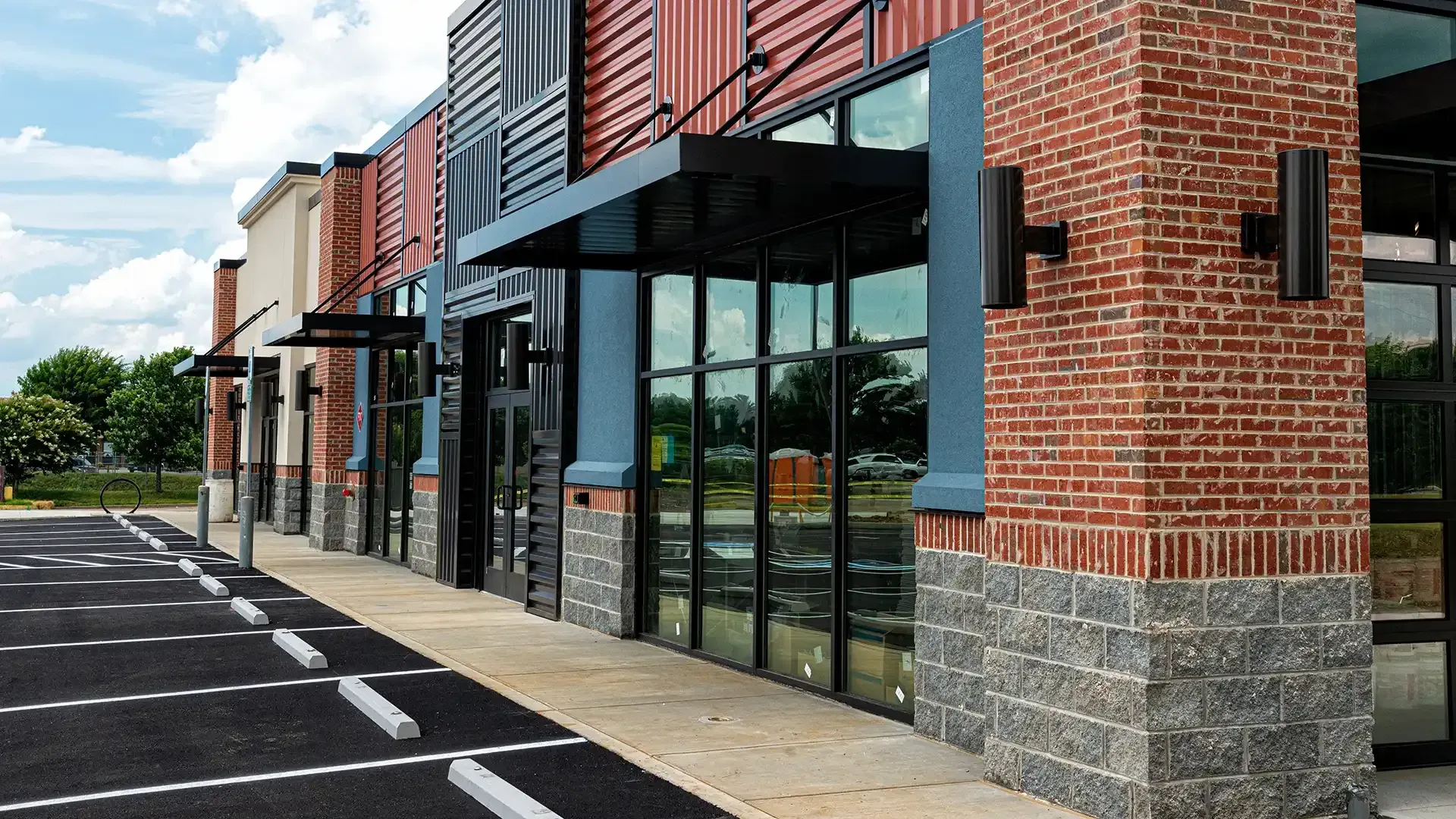 Un bâtiment en briques avec beaucoup de fenêtres et un parking devant.