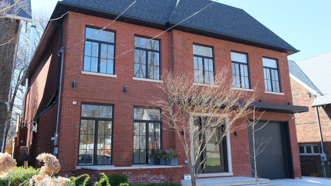 Une grande maison en briques rouges avec des fenêtres noires et un toit noir.