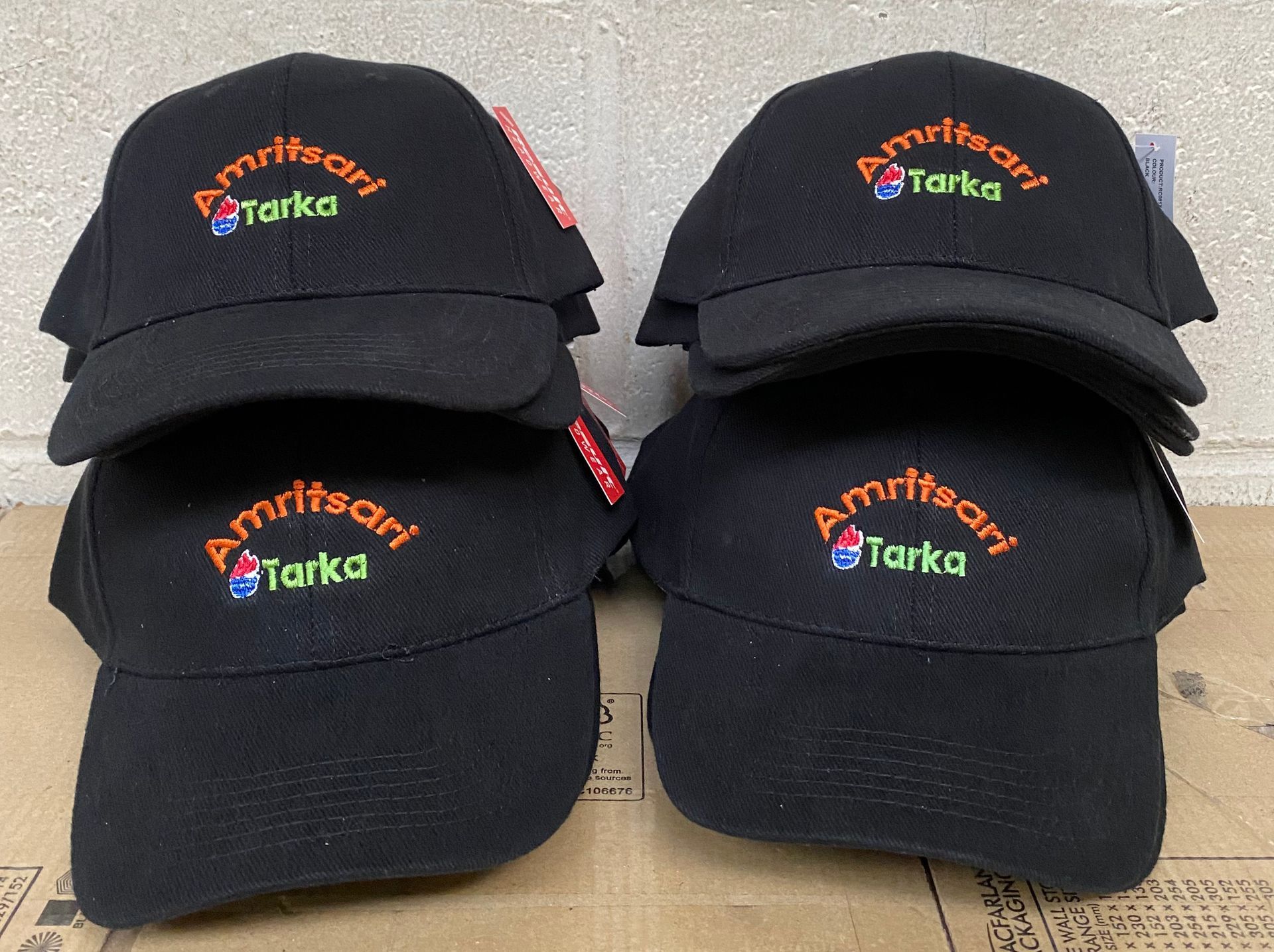 Four black caps stacked, each embroidered with