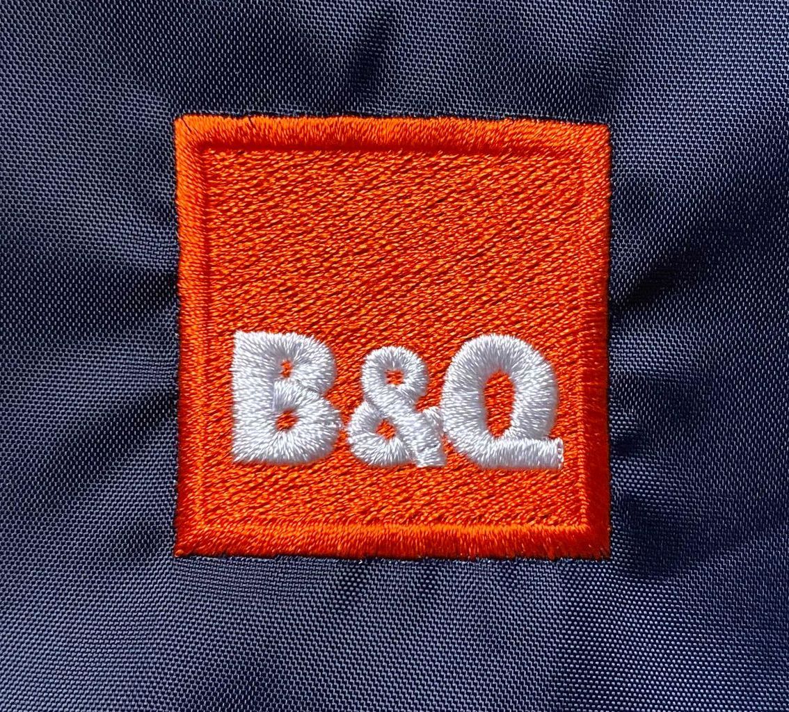 Embroidered orange square patch with the letters