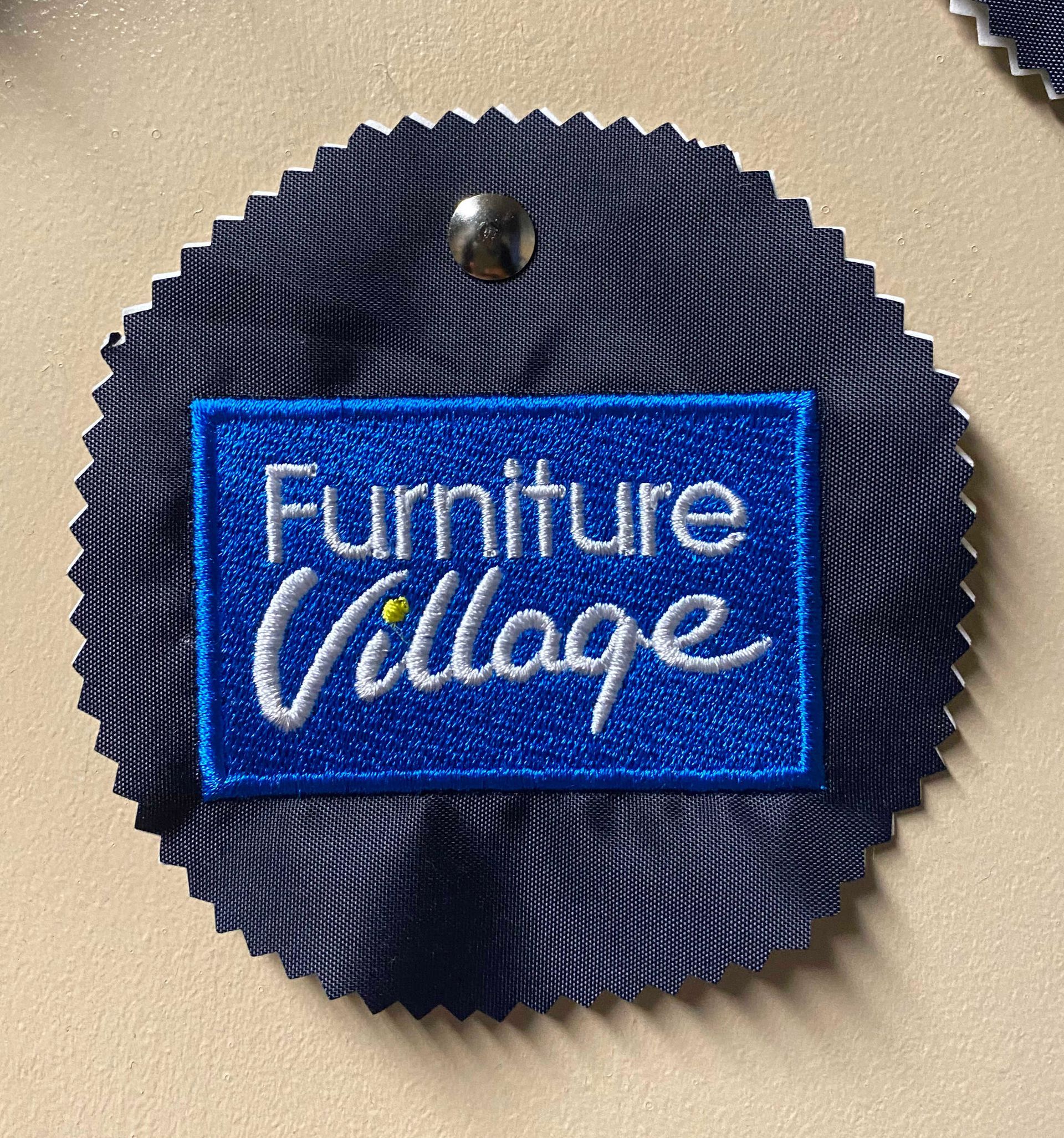 A dark blue fabric rosette with a embroidered