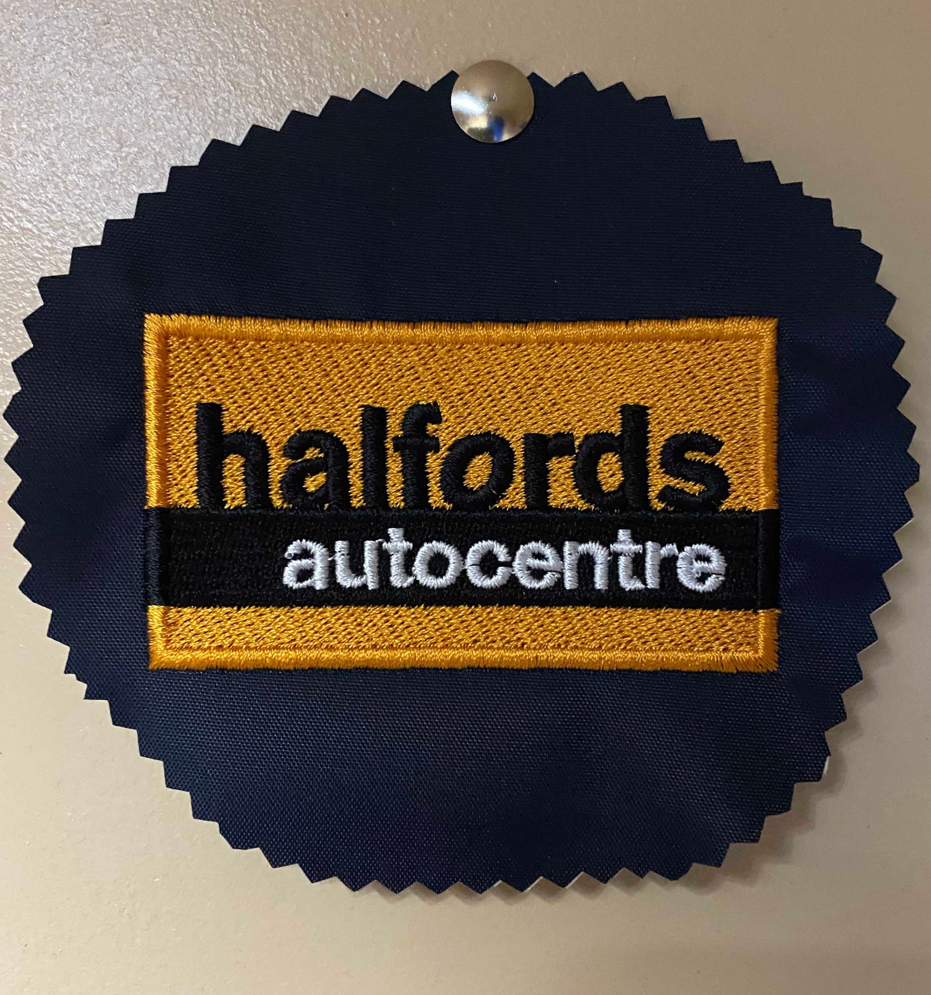 Embroidered Halfords autocentre logo on a navy blue, scalloped-edge tag, secured by a silver tack.