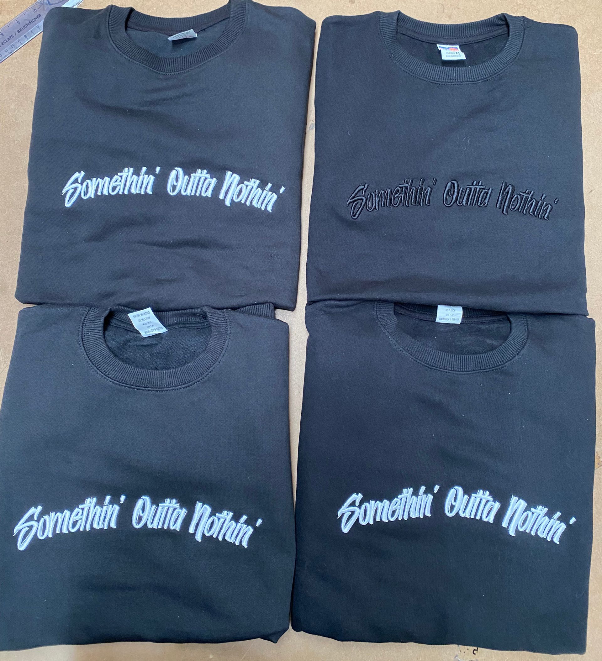 Four black sweatshirts with white and black 3D embroidered text reading