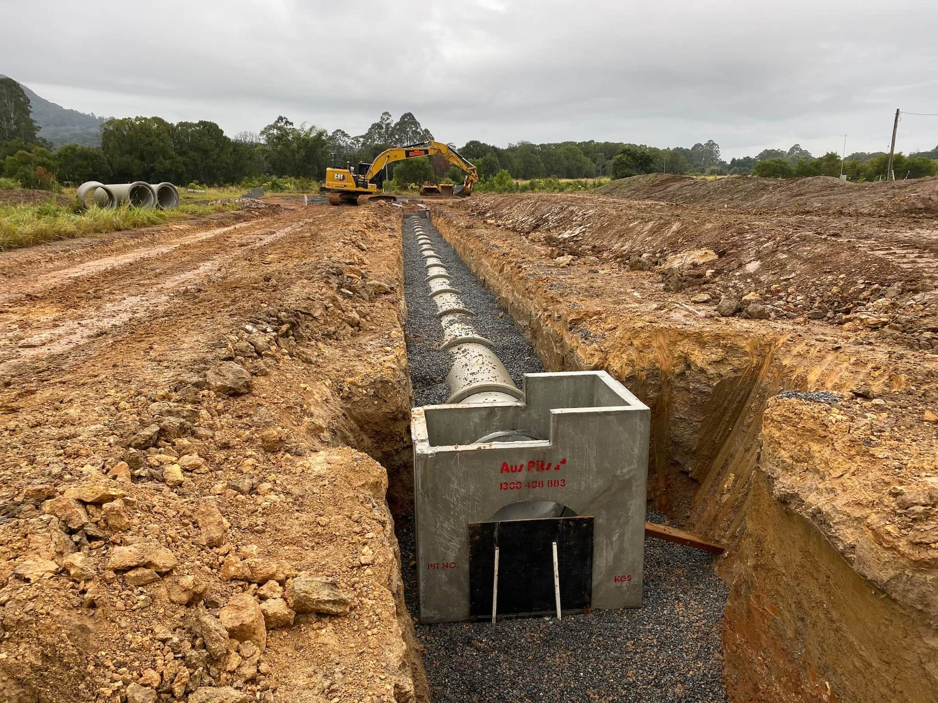 A Pipe Is Being Installed in A Trench in A Dirt Field — J & M Bashforth & Sons In Murwillumbah, NSW