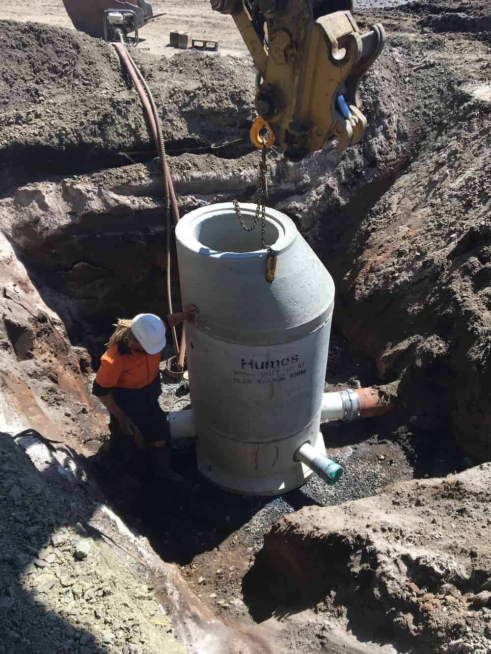 A Construction Worker Is Lifting a Large Concrete Cylinder Into a Hole — J & M Bashforth & Sons In Pottsville, NSW