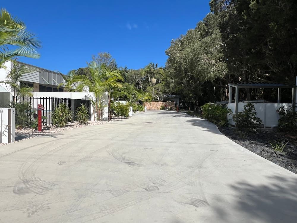 A Concrete Driveway Leading To A House With Trees On Both Sides — J & M Bashforth & Sons In Brunswick Heads, NSW