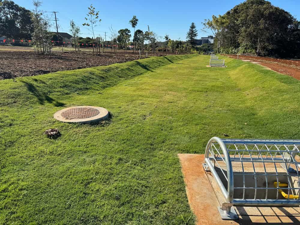 A Manhole Cover Is Sitting In The Middle Of A Lush Green Field — J & M Bashforth & Sons In Brunswick Heads, NSW