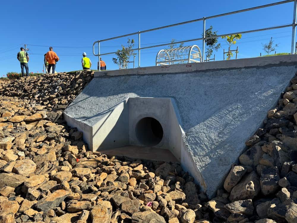 A Group Of People Standing On Top Of A Rocky Hill Next To A Pipe — J & M Bashforth & Sons In Brunswick Heads, NSW