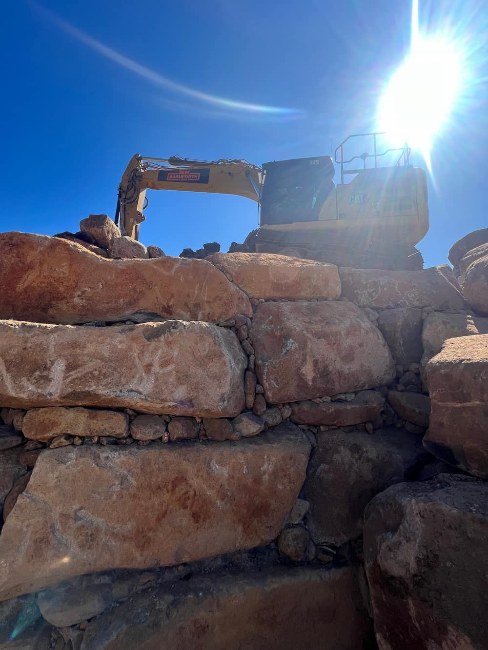 A Bulldozer Is Sitting On Top Of A Pile Of Rocks — J & M Bashforth & Sons In Brunswick Heads, NSW