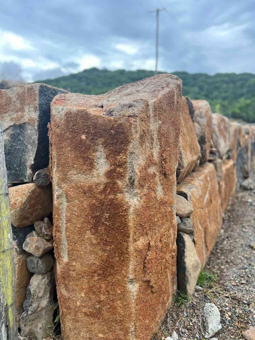 A Close Up Of A Stone Wall With A Mountain In The Background — J & M Bashforth & Sons In Brunswick Heads, NSW