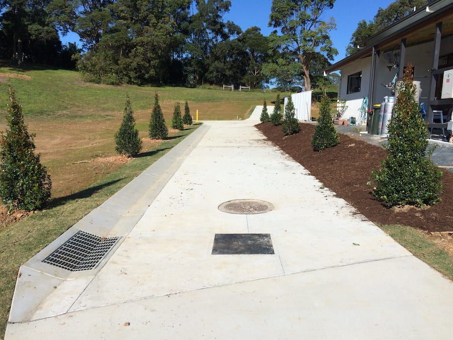 A Concrete Driveway Leading To A House With Trees On The Side — J & M Bashforth & Sons In Brunswick Heads, NSW