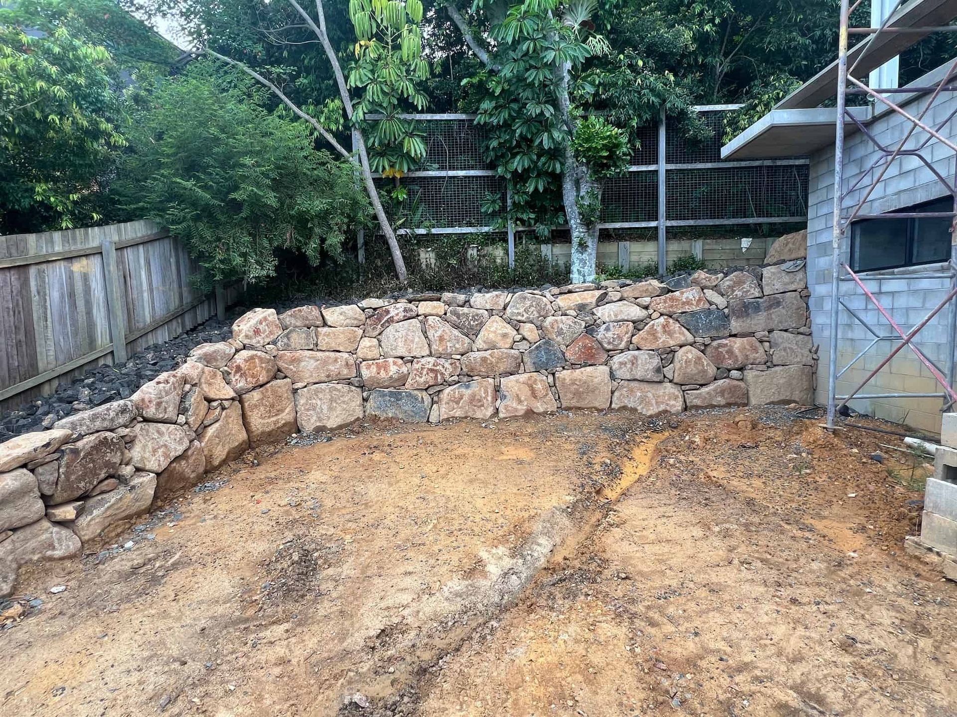A Stone Wall Is Being Built in The Backyard of A House — J & M Bashforth & Sons In Casino, NSW