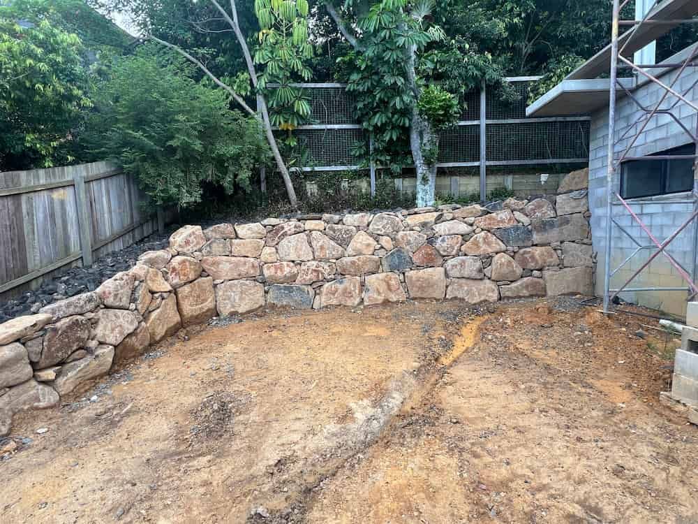 A Stone Wall Is Being Built In The Backyard Of A House — J & M Bashforth & Sons In Brunswick Heads, NSW