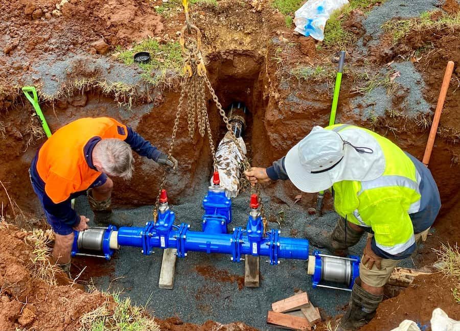 Two Men Are Working On A Pipe In The Dirt — J & M Bashforth & Sons In Brunswick Heads, NSW