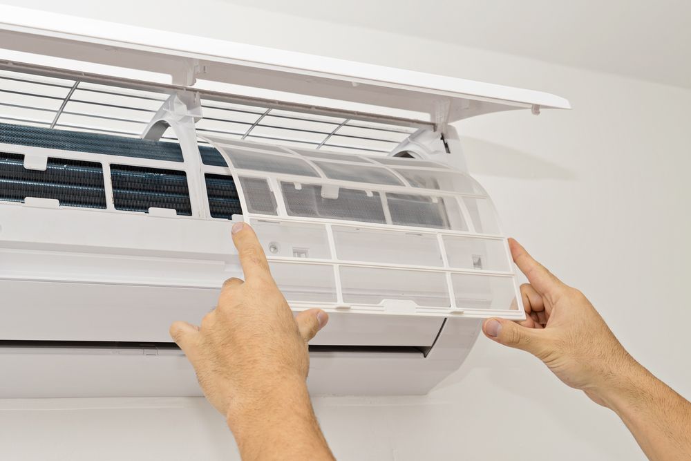 Hands Removing an Air Conditioner Filter From the Unit — A Step Above Electrical & Air Conditioning In Edmonton, QLD