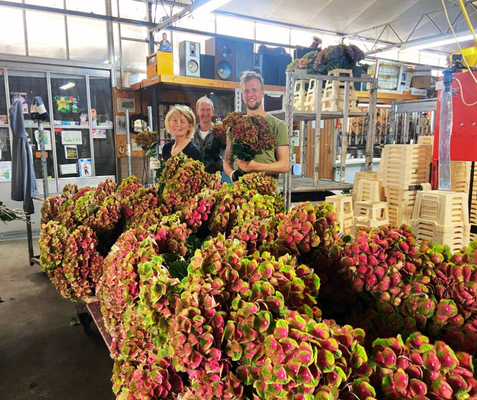 Een groep mensen die voor een bos bloemen staat.