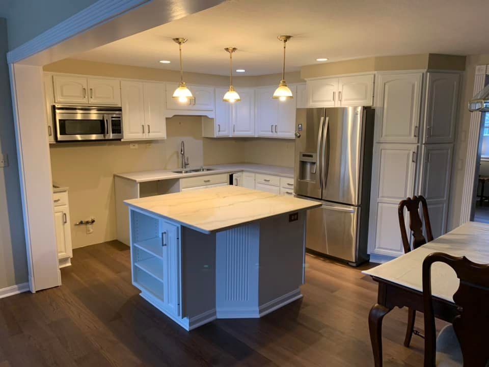 square island, white cabinets, new stainless steal refrigerator and vinyl plank flooring for a kitchen remodel in pittsburgh