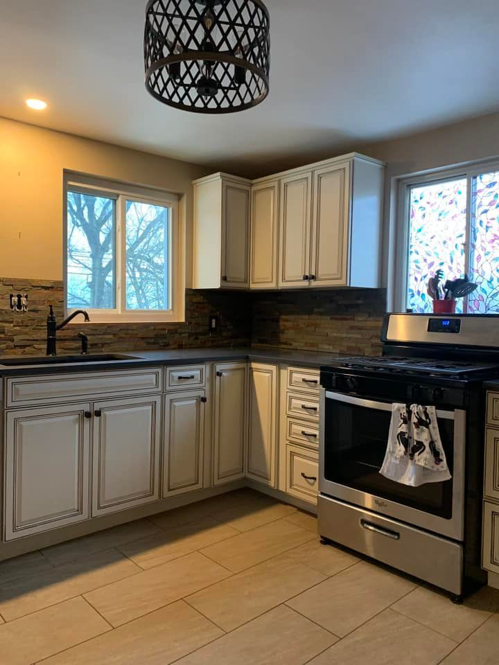 white cabinet kitchen remodel with new stove and backsplash with dark kitchen countertops