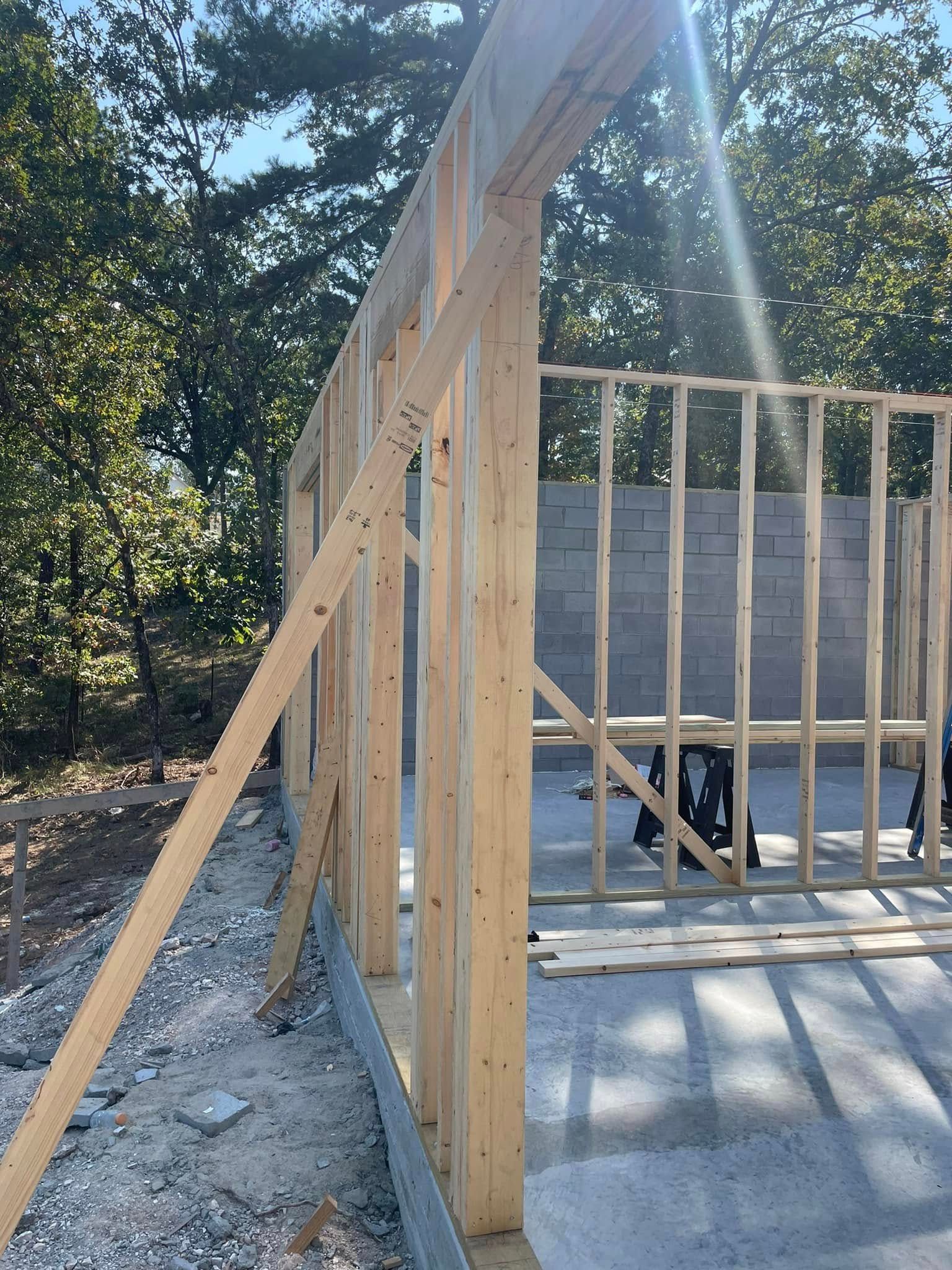 Wooden frame of a building under construction, studs and header visible, outdoors.