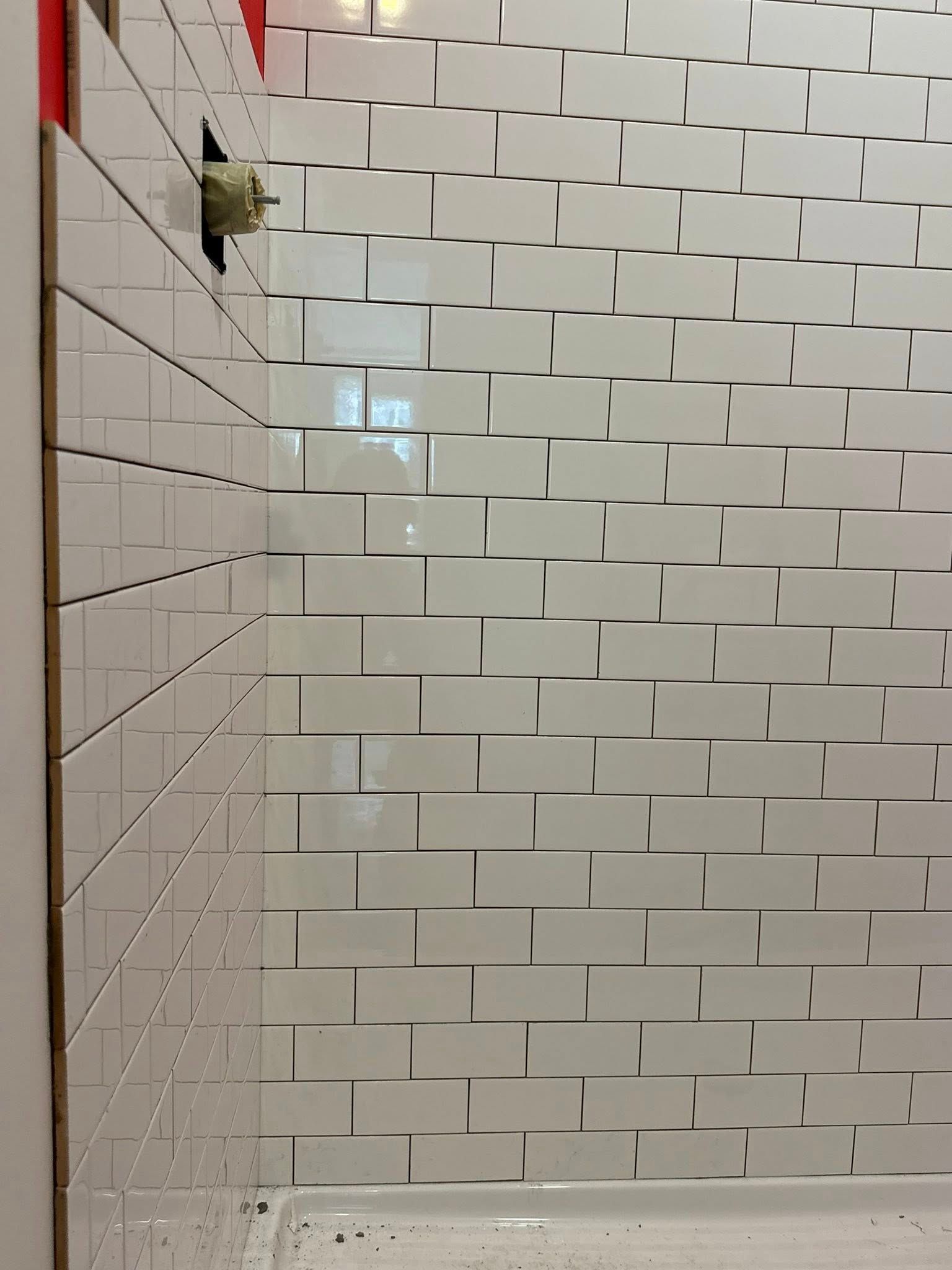 White subway tile shower wall under construction; partially tiled.
