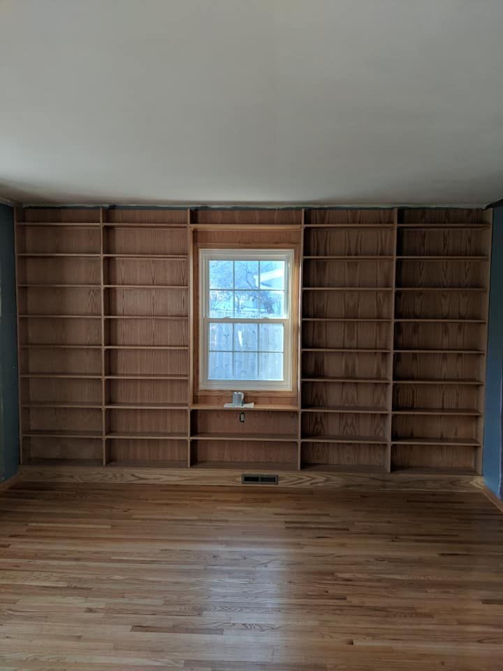 Built-in bookshelves flanking a window on a wood-floored wall. The walls are blue, and the ceiling is white.