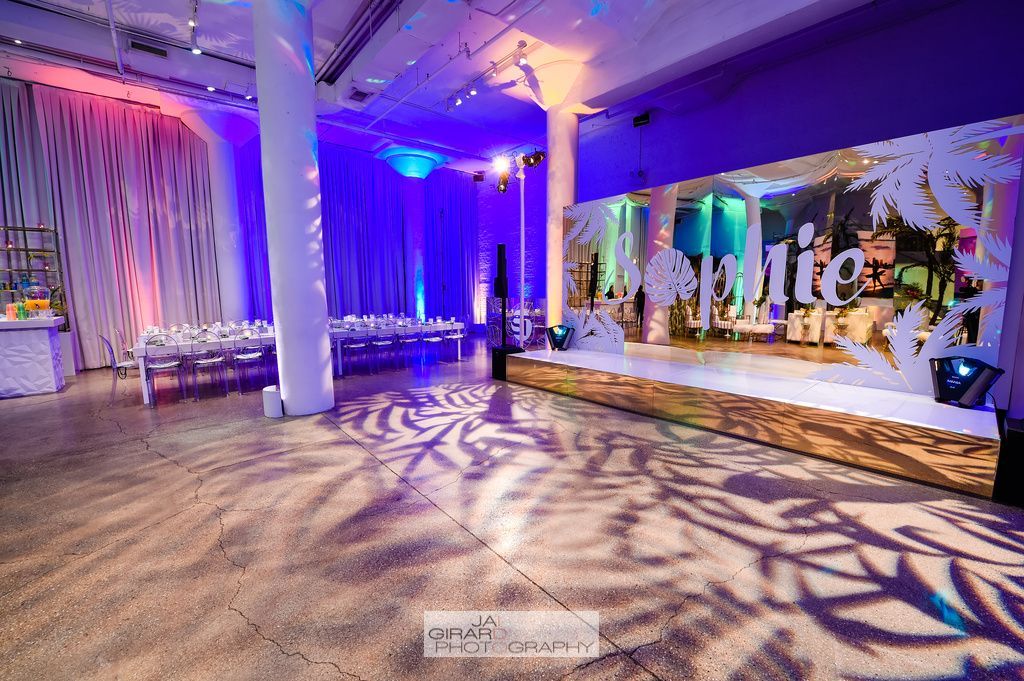 A large room with purple lights and a stage in the middle of it.