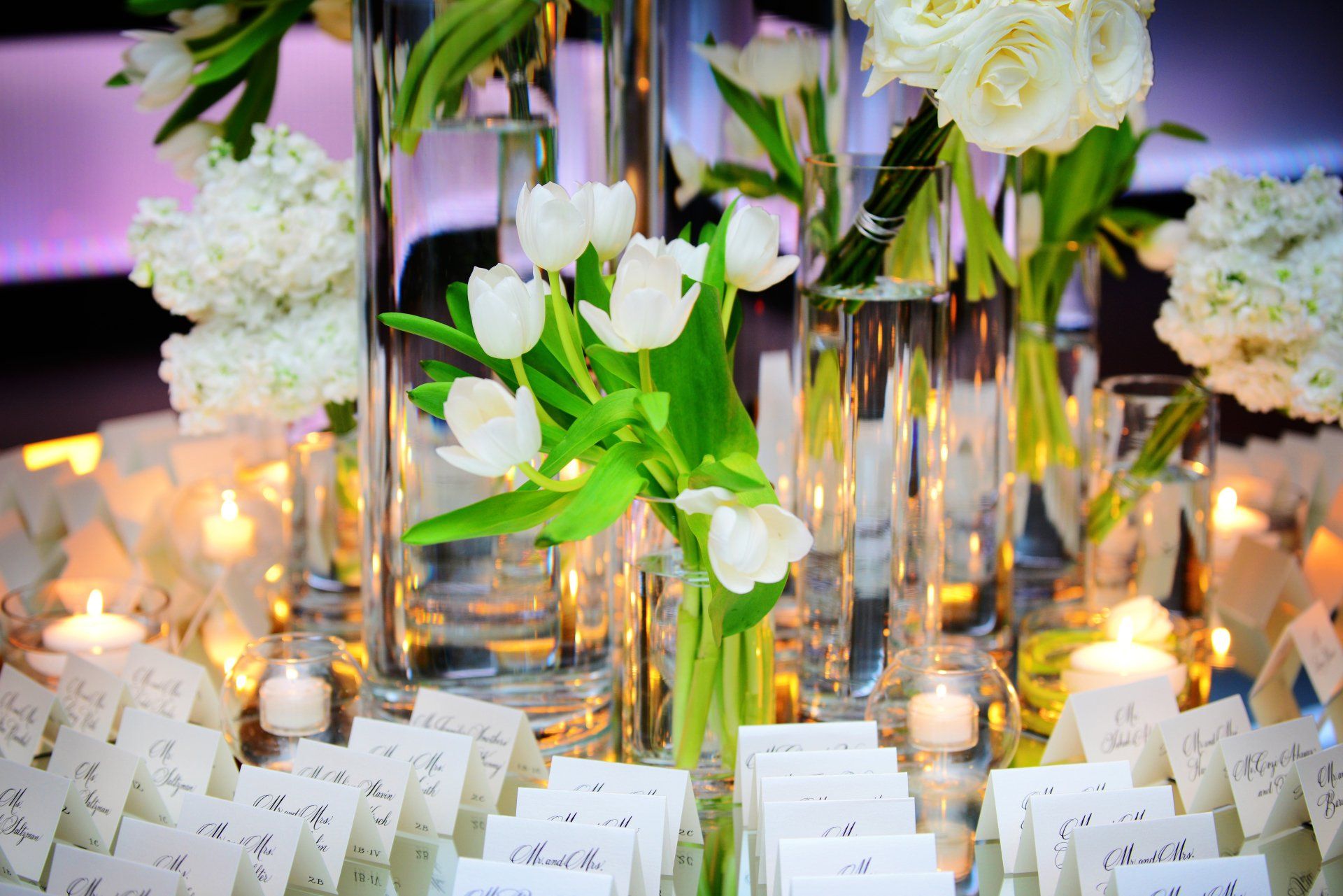 A table with white flowers and candles on it