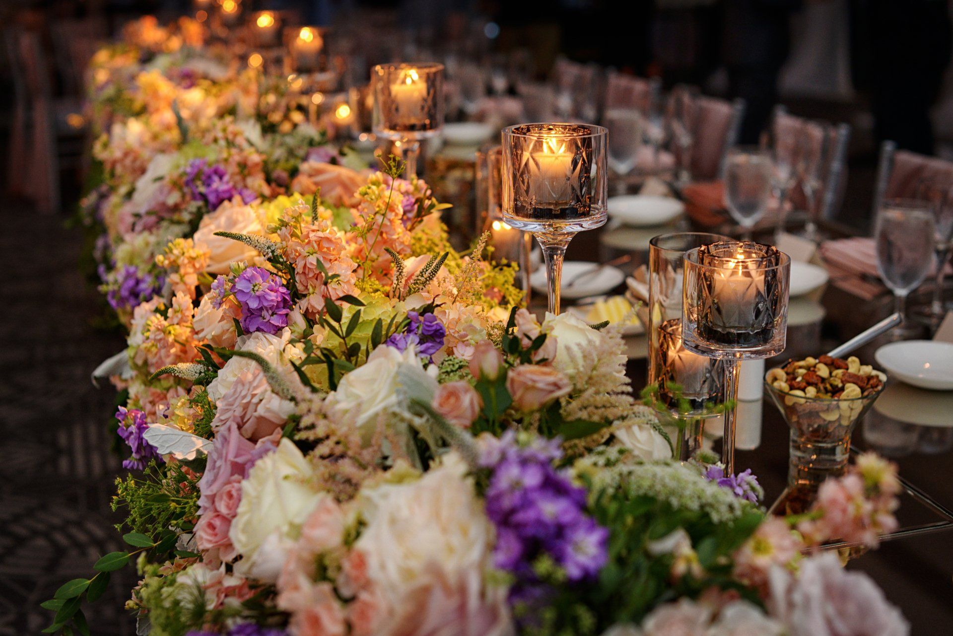 A long table with flowers and candles on it.