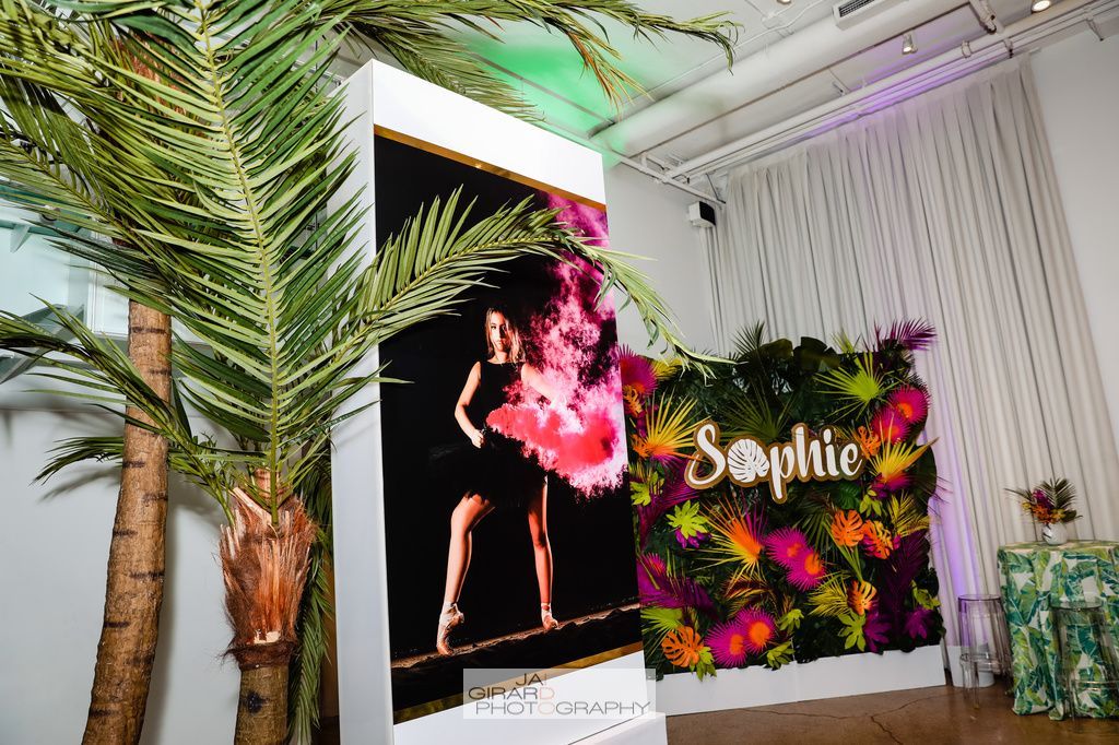 A picture of a woman in a pink dress is on a wall in a room with palm trees.