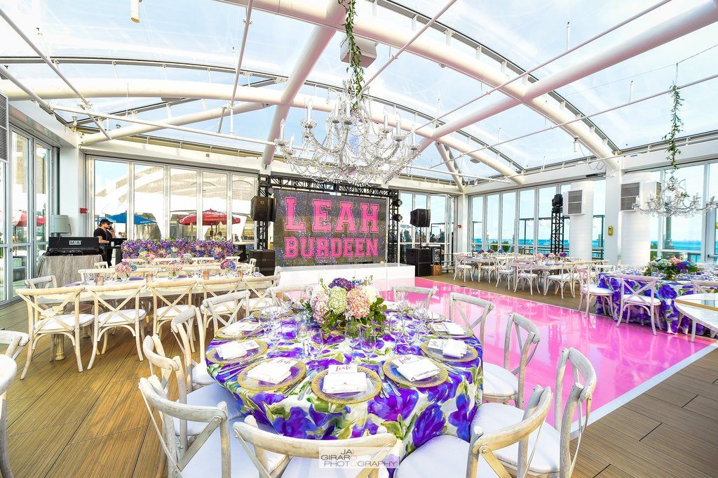 A large room with tables and chairs and a pink dance floor.